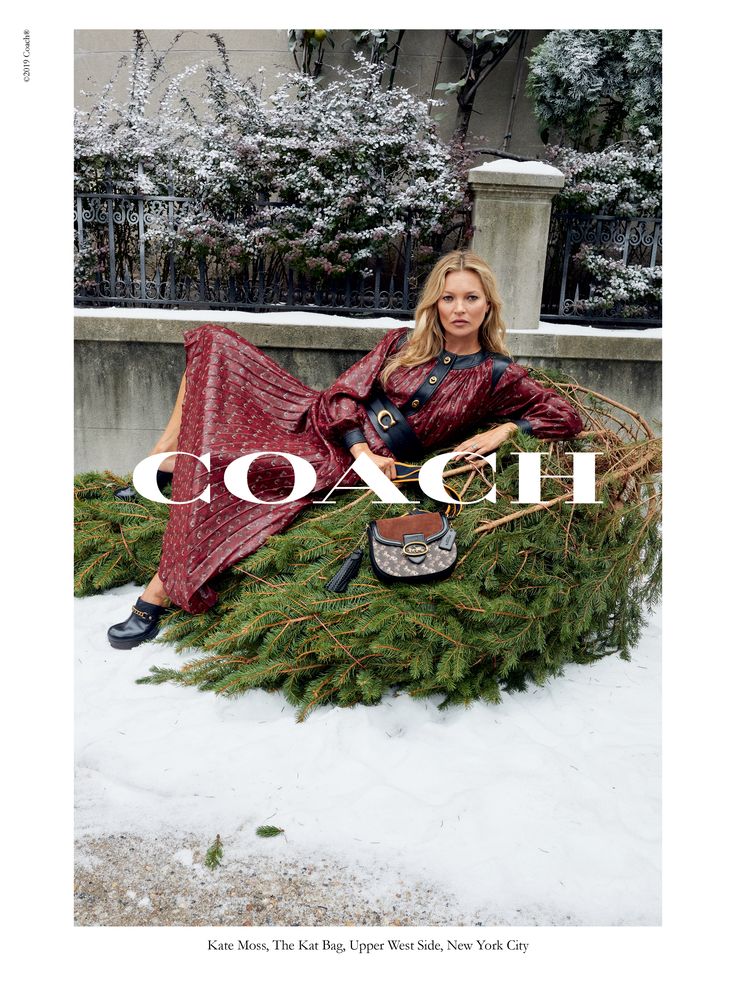 a woman sitting on top of a pile of christmas tree branches in front of a building