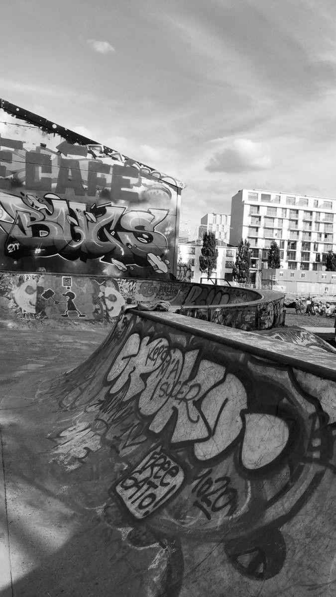 black and white photograph of a skateboarder doing a trick in the air at a skate park