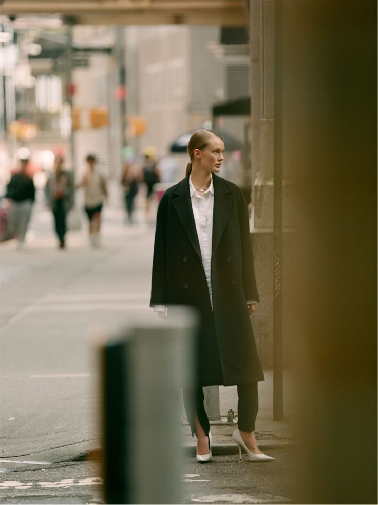 a woman is standing on the side walk