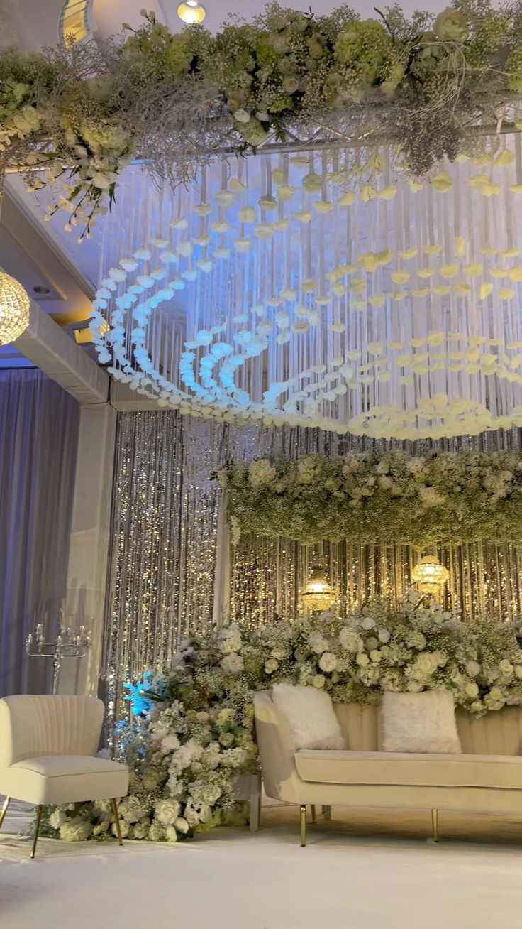 an elegant wedding setup with chandeliers and flowers on the wall, couches and chairs