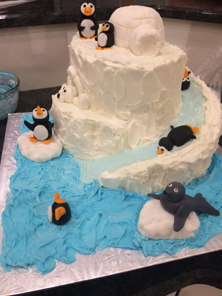 there is a cake with penguins on it and an iceberg in the middle, as well as penguin figurines