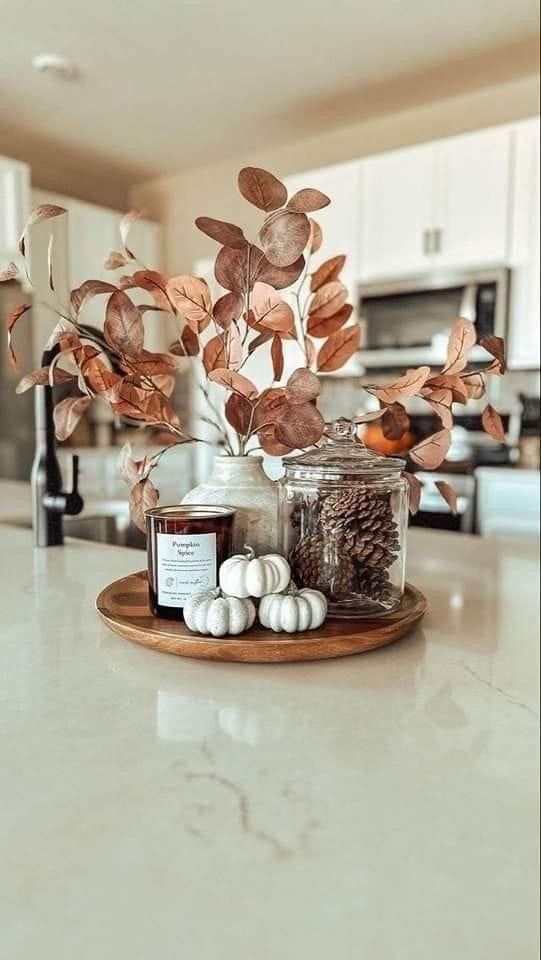 a white counter top topped with jars filled with plants and candles on top of it