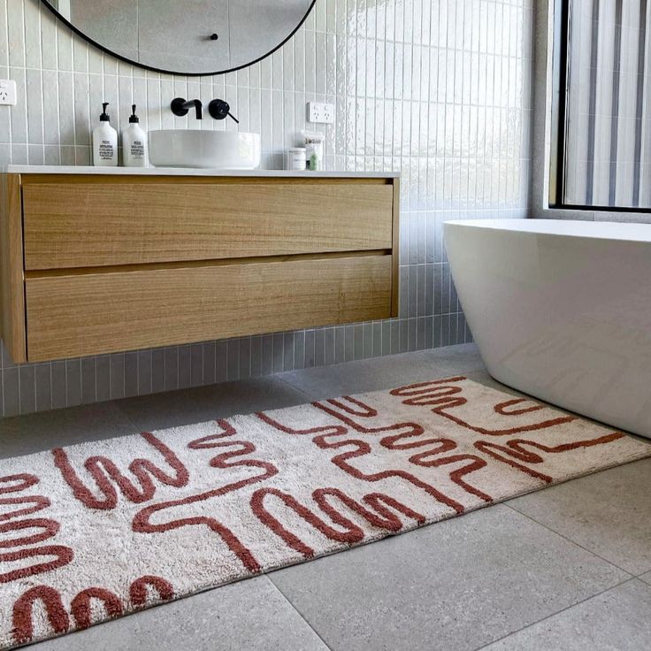 a bathroom with a bathtub, sink and rug on the floor in front of it