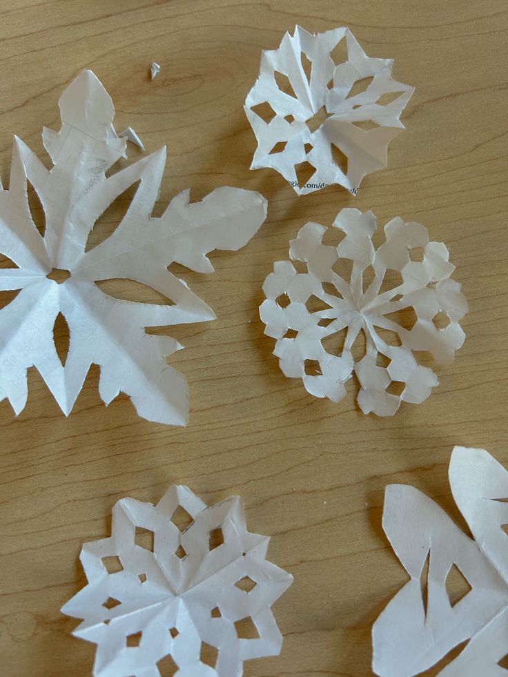 paper snowflakes sitting on top of a wooden table