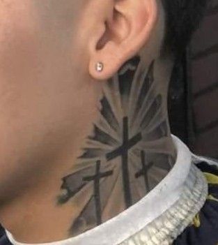 a man with a cross tattoo on his neck and behind his ear is looking at the camera