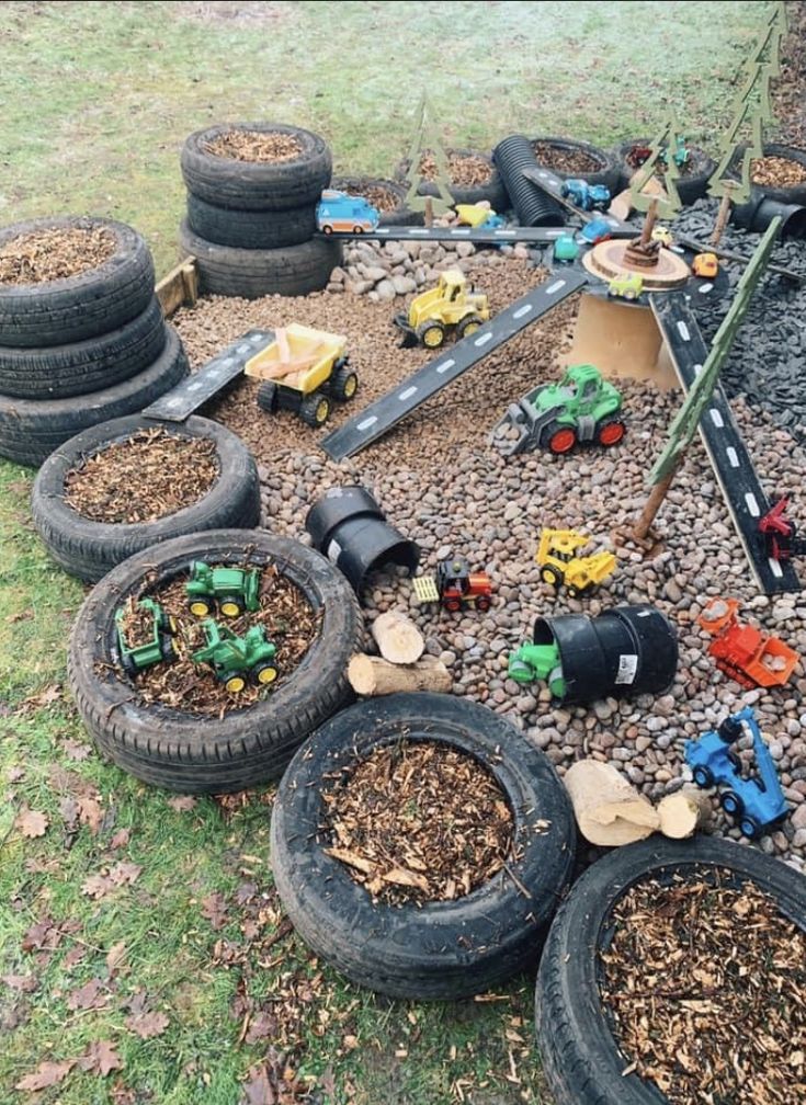 a pile of tires sitting on top of a grass covered field next to toy cars