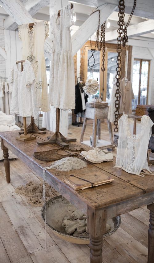 a wooden table topped with lots of white clothing hanging from it's sides in a room