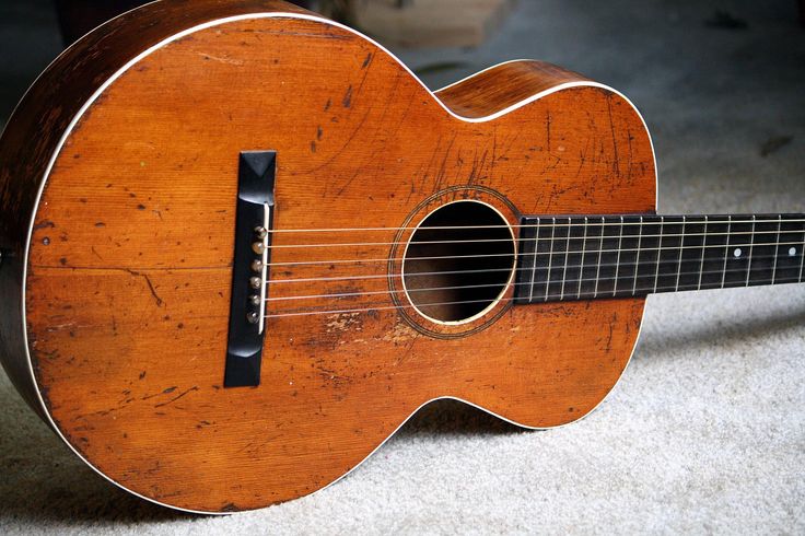 an old guitar sitting on the floor with it's strings still attached to it