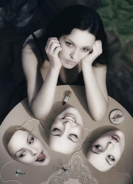 a woman is sitting at a table with four faces on it and one has her hands to her face