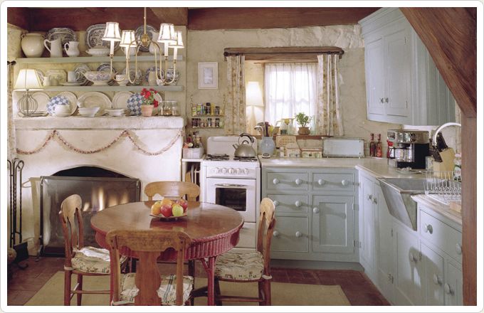 an old fashioned kitchen with white appliances and wood beams on the ceiling, along with a fireplace