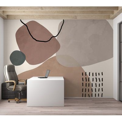 an office with a desk and chair in front of a wall mural that has abstract shapes on it