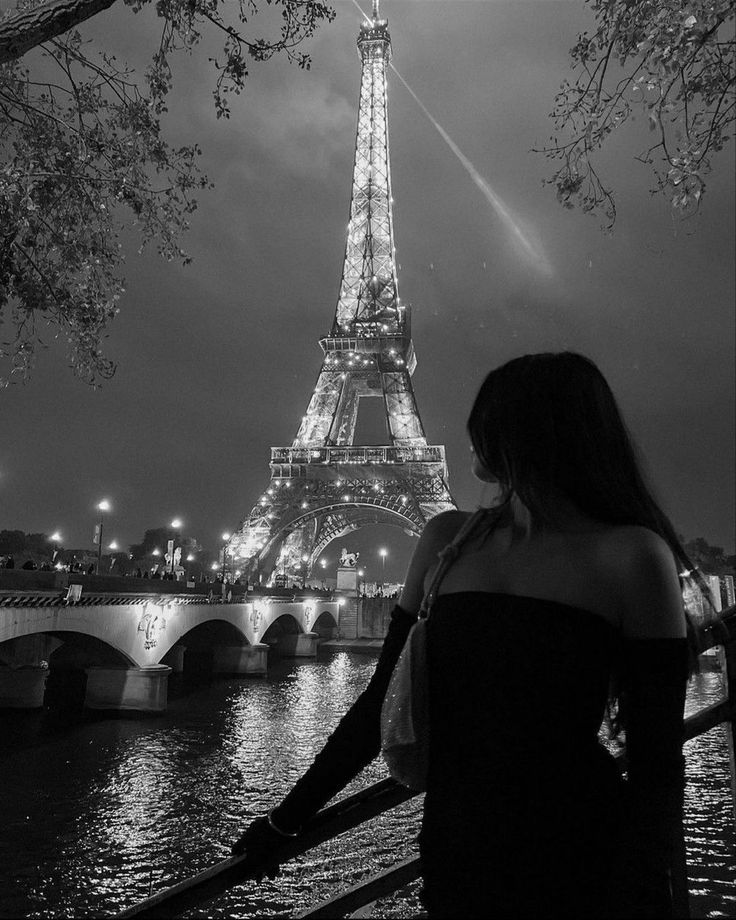 a woman standing in front of the eiffel tower with her back to the camera