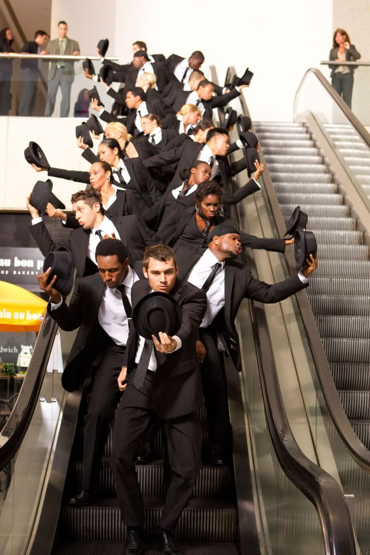 a group of men in suits and ties riding an escalator with their arms around each other