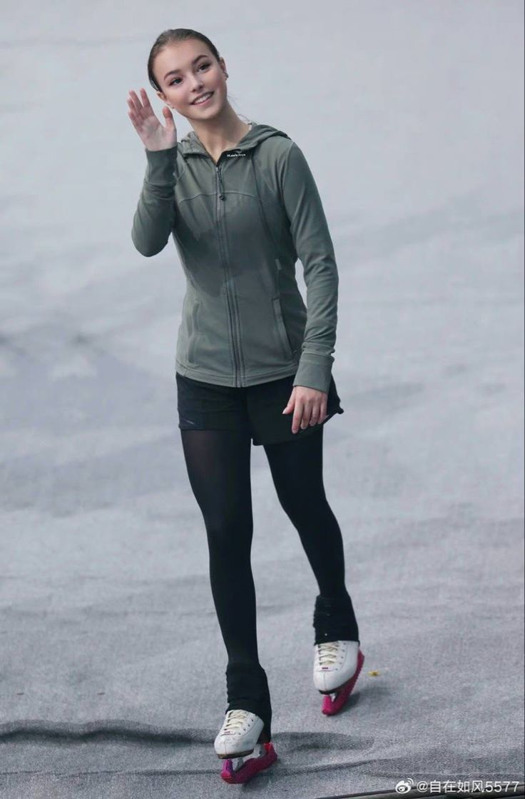 a woman in black tights and a green jacket is riding on roller skates