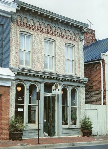 an old brick building on the corner of a street with potted plants in front