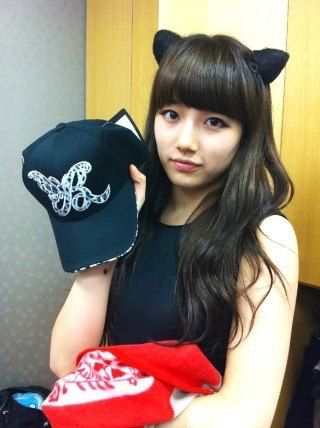 a girl in a black top is holding a baseball cap