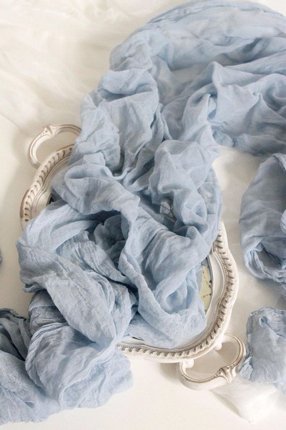 a blue scarf is laying on top of a white table with a mirror and other items around it