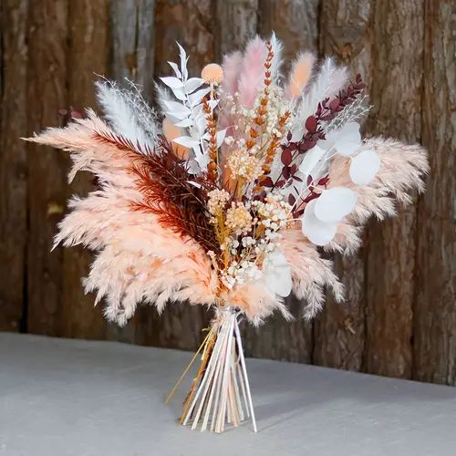 a vase filled with feathers and flowers on top of a table