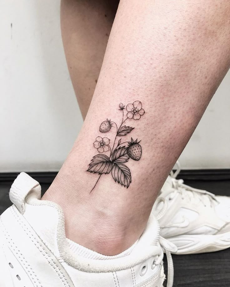 a woman's foot with a small flower tattoo on the left side of her leg