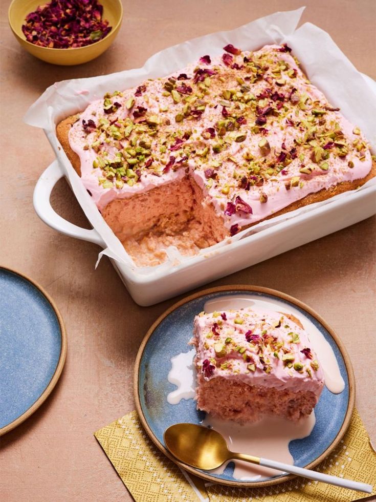 a cake with pink frosting and sprinkles sits on a blue plate