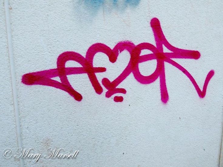 graffiti written on the side of a building with blue and red spray paint in the shape of a heart