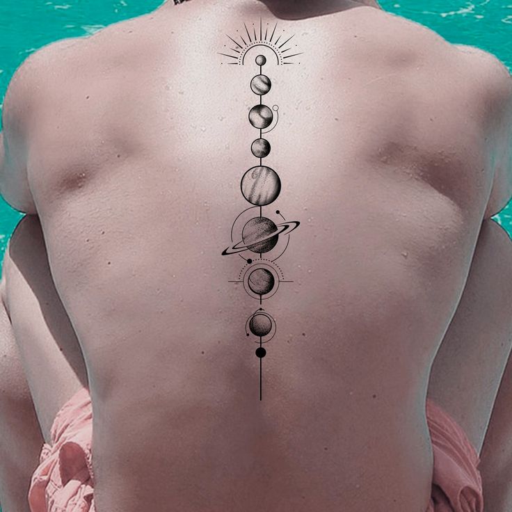 the back of a woman's body with tattoos on it, including planets and sun