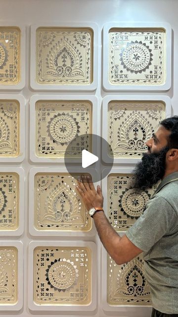 a man standing in front of a wall covered with intricately designed tiles and looking up at the ceiling