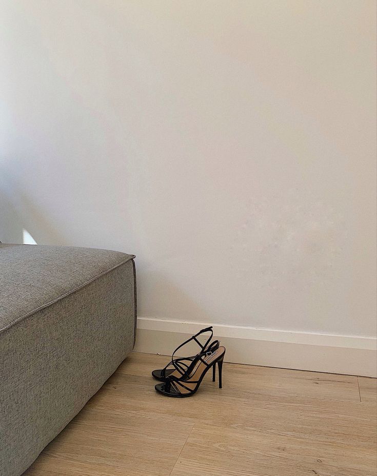 a pair of black high heeled shoes sitting on the floor next to a couch