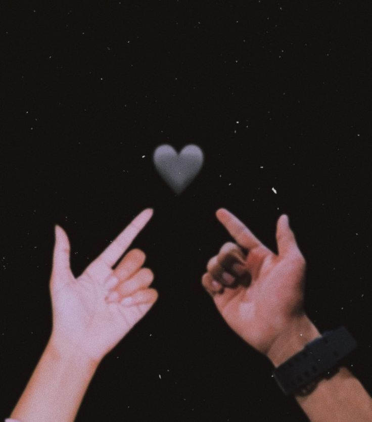 two hands reaching up towards each other with a heart shaped object in the sky behind them