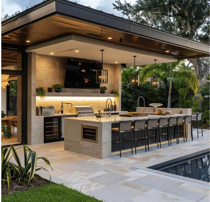 an outdoor kitchen and dining area next to a pool