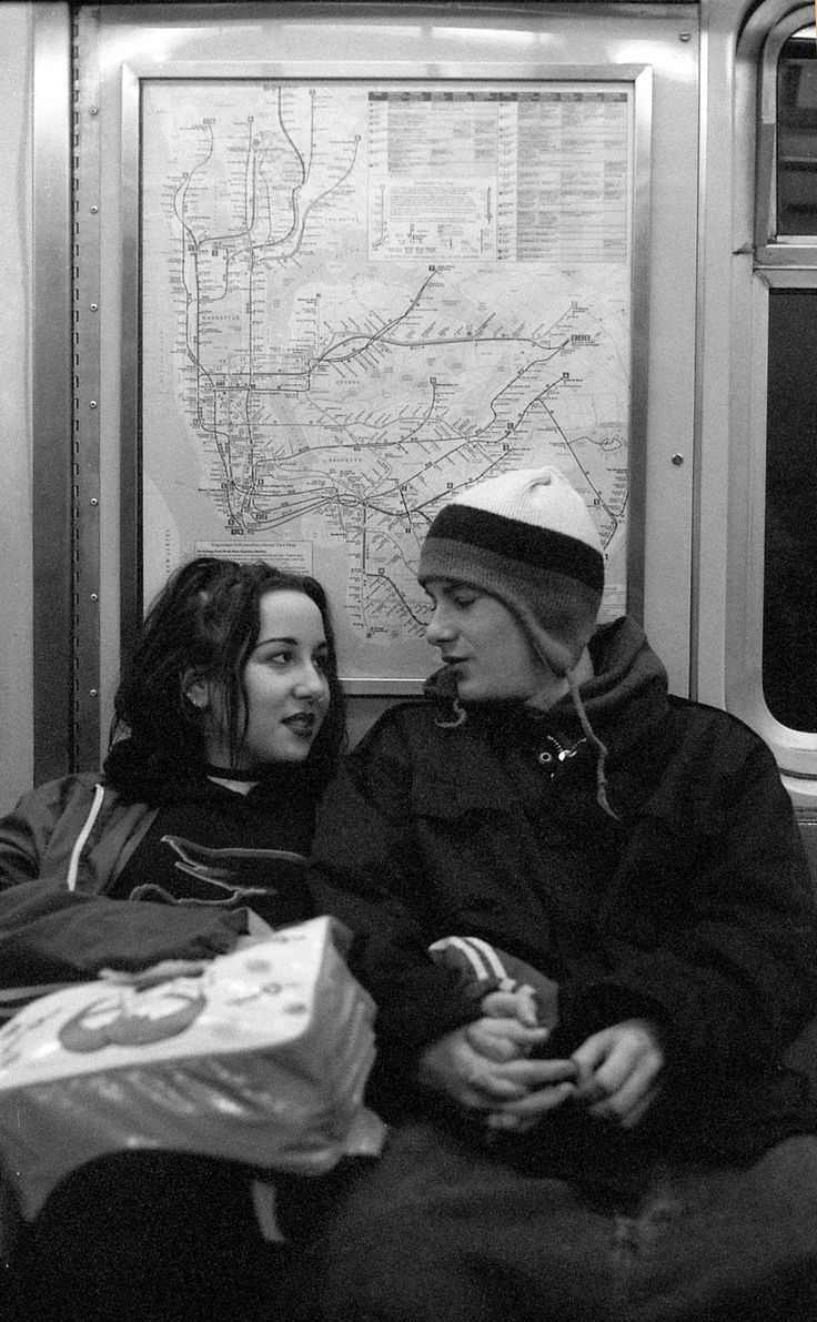 a man and woman sitting on a subway train looking at each other's faces