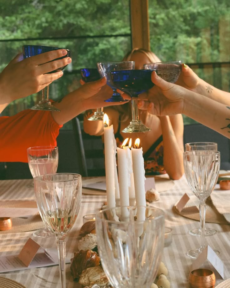 people are toasting with wine glasses and candles on a table in front of them