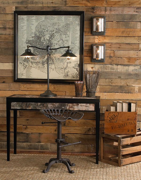 a table with a lamp on it in front of a wooden wall and some crates