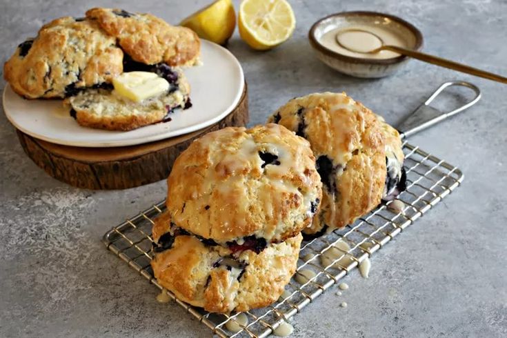 blueberry muffins on a cooling rack next to a bowl of milk and lemon wedges