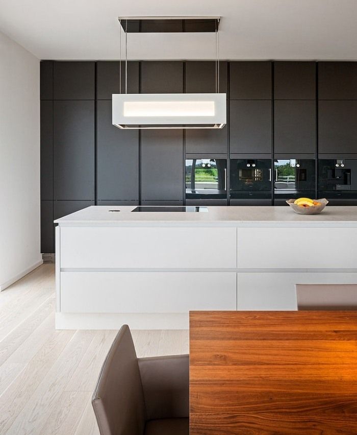 an iphone photo of a kitchen with black cabinets and white countertops, along with a wooden dining table