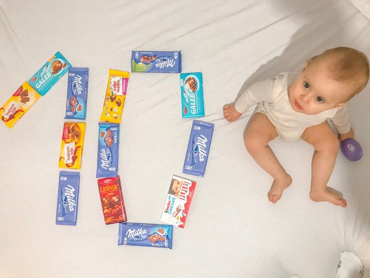 a baby laying on top of a bed next to candy bars