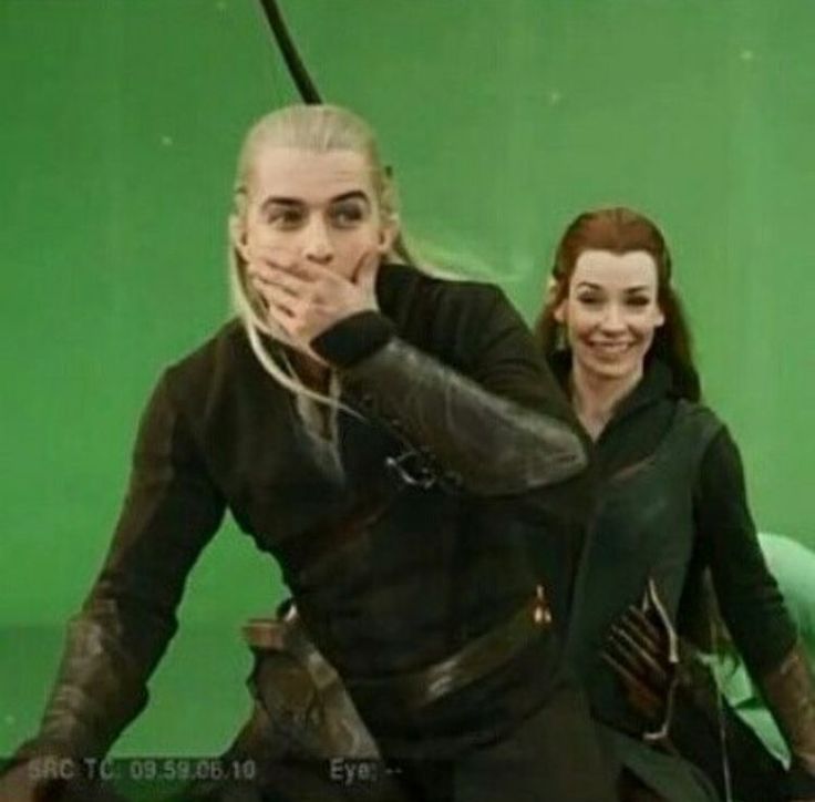 a man and woman dressed in black standing next to each other on a green screen