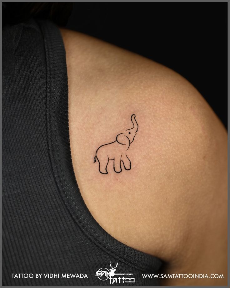 an elephant tattoo on the back of a woman's left shoulder, which is drawn in black ink