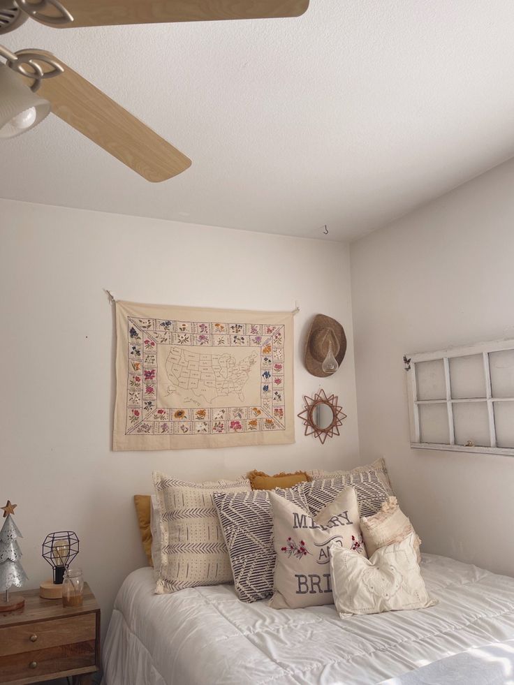 a bedroom with a bed, ceiling fan and pictures hanging on the wall above it