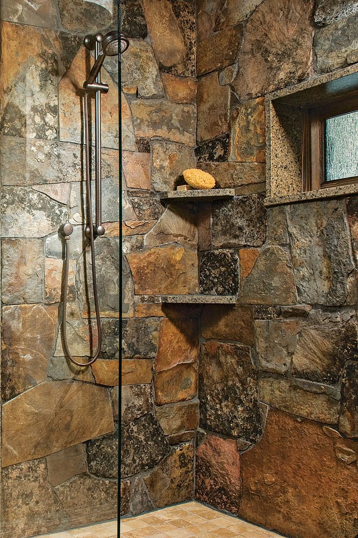 a shower with stone walls and shelves in the corner, along with a tiled floor