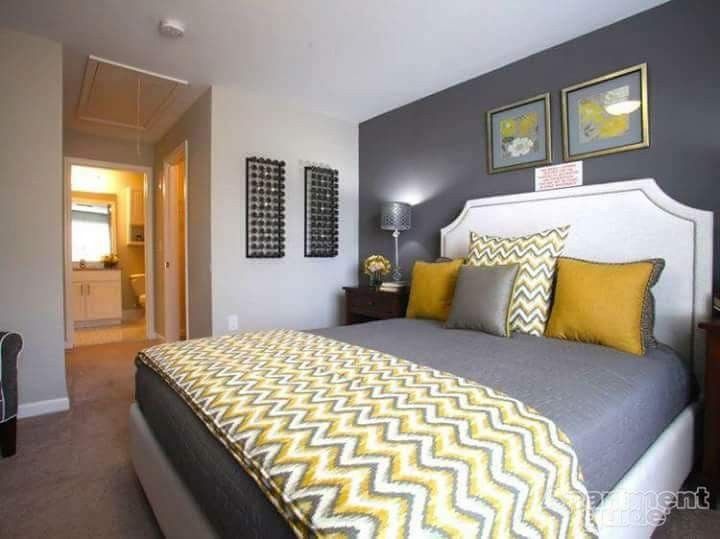 a bedroom with gray walls and yellow pillows on the bed, along with two framed pictures