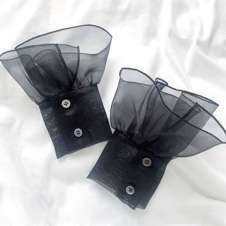 two pieces of black organe fabric with buttons on the front and back of each piece