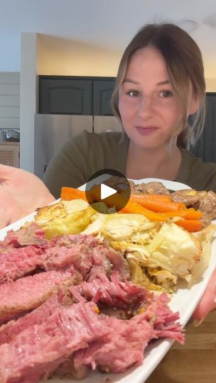 a woman is holding a plate with meat and veggies on it in front of her