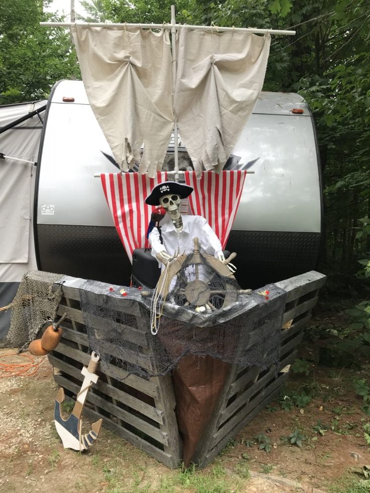 a pirate statue sitting on top of a wooden crate in front of a camper