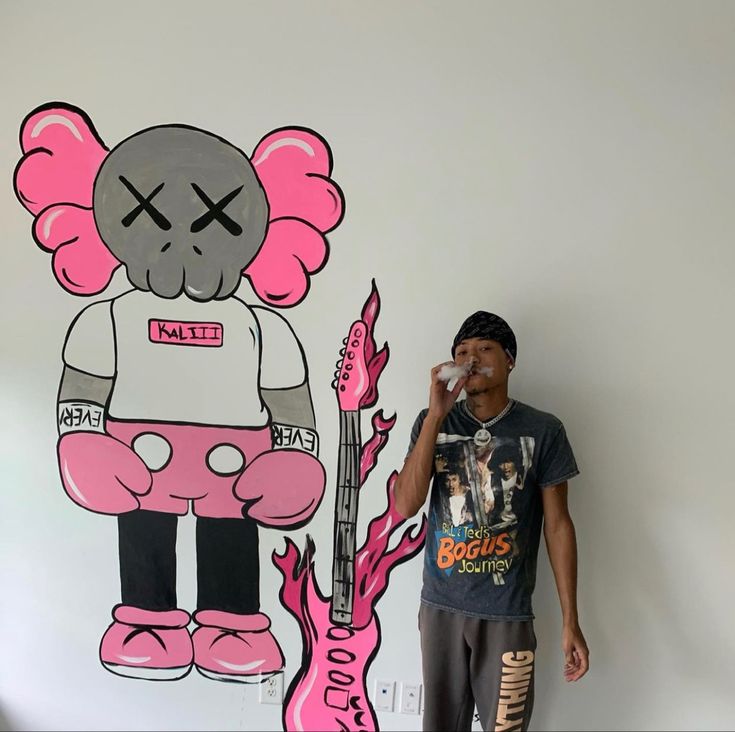 a man standing in front of a wall with a cartoon character painted on the side