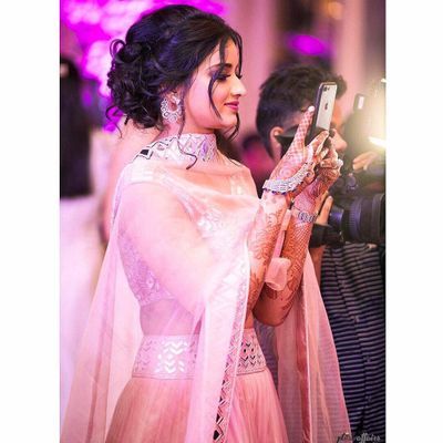 a woman in a pink sari taking a photo with her cell phone at an event