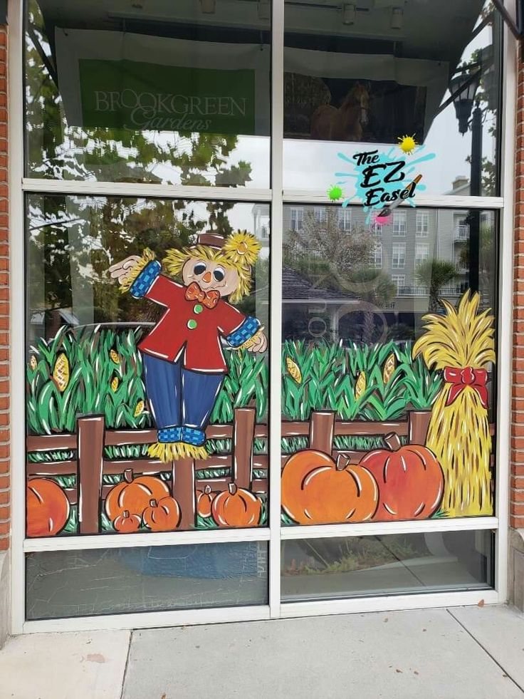 a glass window with an image of a scarecrow and pumpkins painted on it