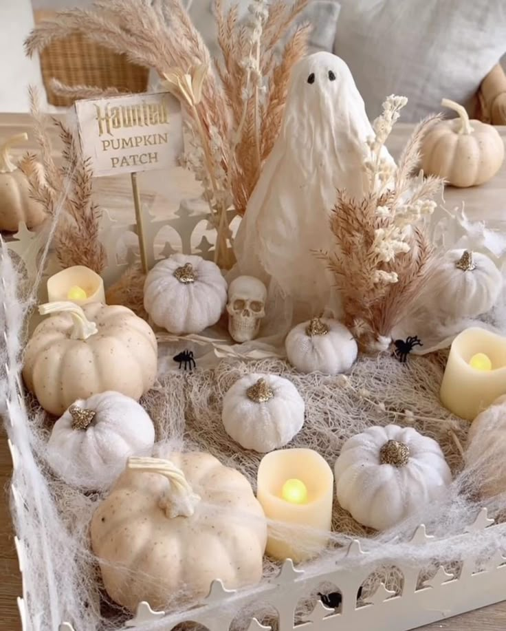 white pumpkins and candles in a basket on a table