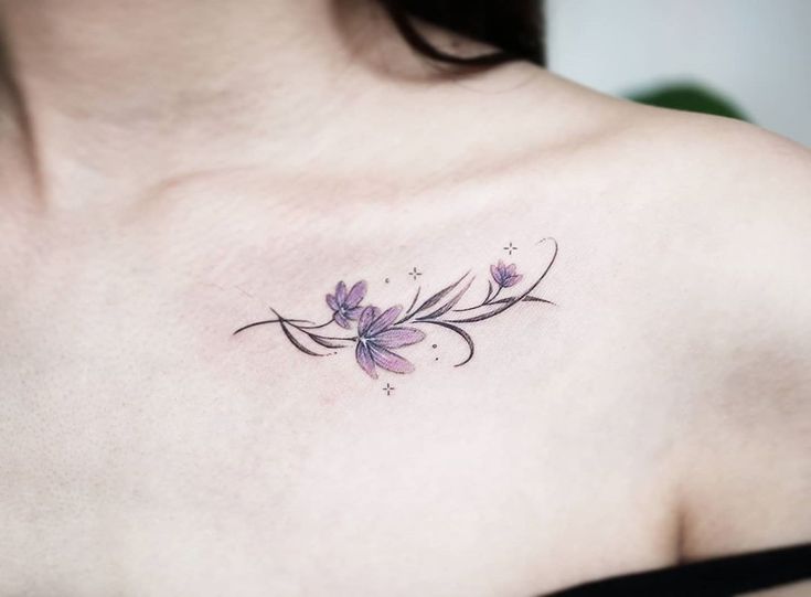 a woman with a tattoo on her chest has a purple flower in the middle of her left shoulder