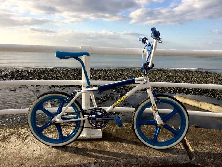 a blue and white bike parked on the side of a road next to the ocean